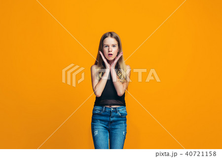 Beautiful teen girl looking suprised isolated on orange Beautiful teen girl looking suprised isolated on orange 40721158
