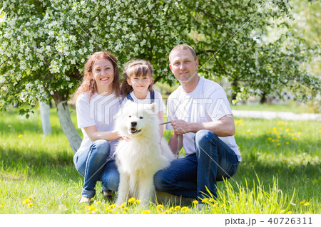 Happy family with a white dog in a summer park. 40726311