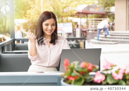Young woman with laptop in cafe holding a pen being very satisfied and successful. Young woman with laptop in cafe holding a pen being very satisfied and successful. 40730344