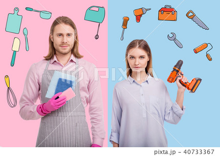 Confident woman holding a drill while her husband standing with washups 40733367