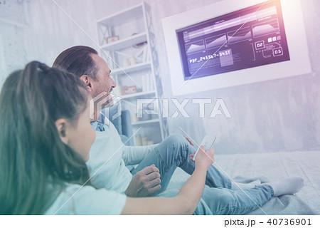 Smiling relatives sitting together and switching channels Smiling relatives sitting together and switching channels 40736901