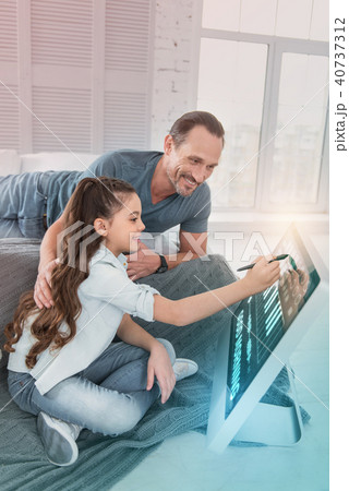Smiling girl sitting near her father and using a modern stylus 40737312