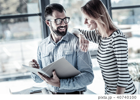Joyful bespectacled man smiling and looking at his colleague. 40740100