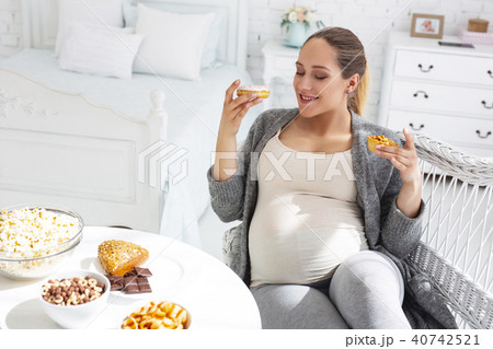 Doubtful pregnant woman choosing French pastry Doubtful pregnant woman choosing French pastry 40742521
