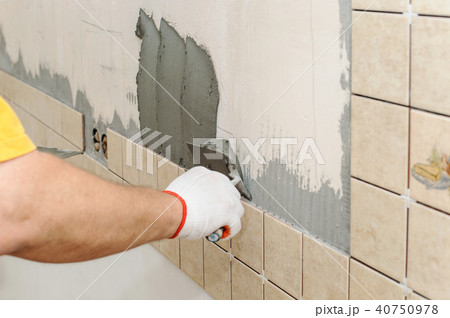 Worker instiling tiles on the wall in the kitchen. 40750978
