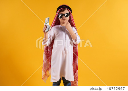 Arabian boy in keffiyeh holds bundle of dollars Arabian boy in keffiyeh holds bundle of dollars 40752967