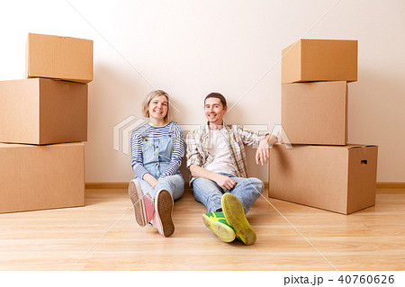 Photo of young married couple sitting on floor among cardboard boxes 40760626