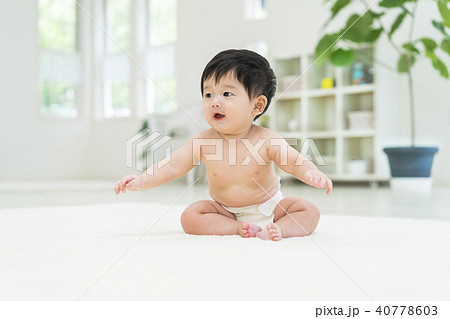 座って両手を広げる赤ちゃんの写真素材
