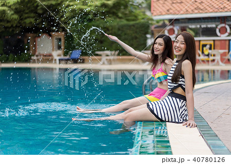 two young woman friends splashing water in swimming pool 40780126