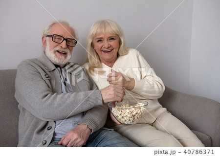 Old couple eating popcorn on sofa. Old couple eating popcorn on sofa. 40786371