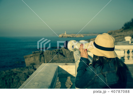 Young girl looking through a coin operated 40787088