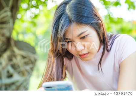 girl using smartphone while sitting on a bench girl using smartphone while sitting on a bench 40791470