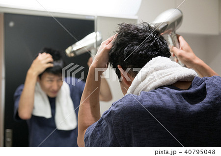 ドライヤーでヘアセットする若い日本人男性の写真素材