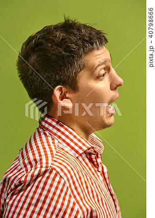 The young attractive man looking suprised isolated on green The young attractive man looking suprised isolated on green 40798666
