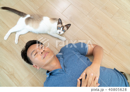 Asian man with elder cat lying on floor at home. Asian man with elder cat lying on floor at home. 40805628