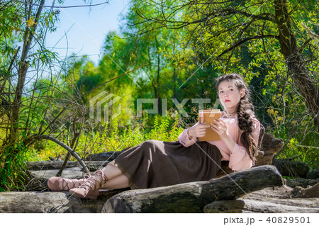 Young woman in a Boho style is reading in fores 40829501