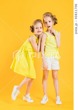 The girls of the twins stand together on a yellow background. The girls of the twins stand together on a yellow background. 40831706