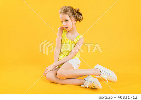 A teenage girl is sitting on a yellow background. A teenage girl is sitting on a yellow background. 40831712