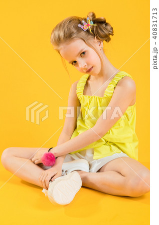 A teenage girl is sitting on a yellow background. 40831713