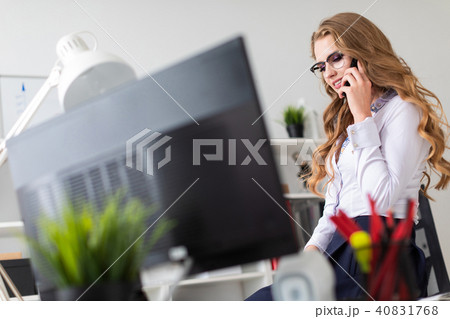 A beautiful young girl sat down on the table in the office and was talking on the phone. Before the 40831768