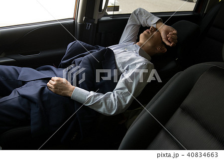 車で仮眠するビジネスマンの写真素材