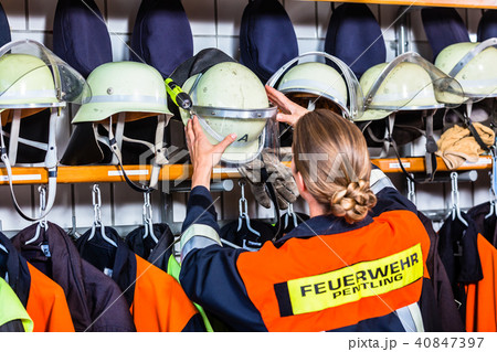 Female fire fighter in the locker room taking helmet 40847397