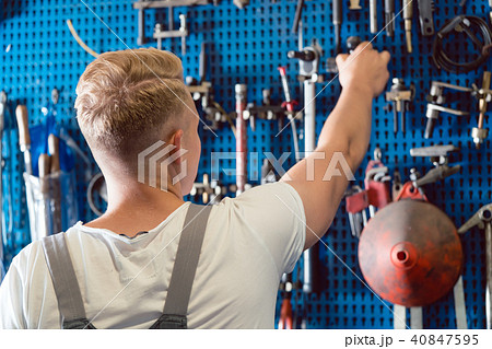 Rear view of a man choosing an useful tool during work in a repair shop 40847595