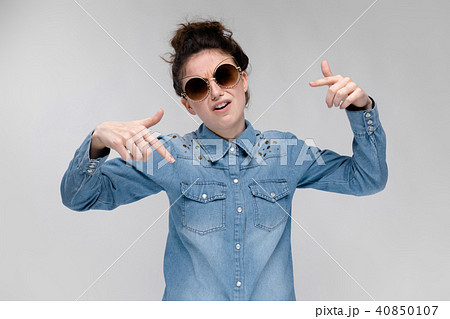Young brunette girl in black glasses. Cat glasses. The hair is gathered in a bun. The girl shows Young brunette girl in black glasses. Cat glasses. The hair is gathered in a bun. The girl shows 40850107