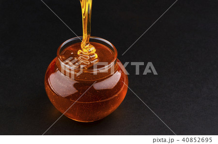 Pot of pouring honey on black background with copy space 40852695