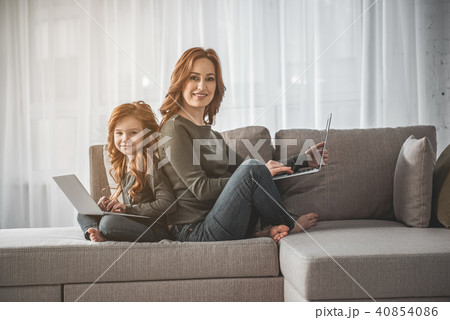 Mom and kid sitting with laptops and laughing at home 40854086