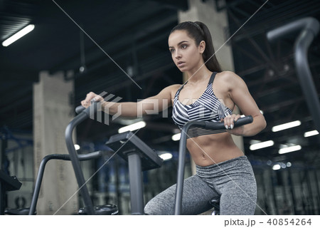Young woman exercises in gym healthy lifestyle cardio workout on bike Young woman exercises in gym healthy lifestyle cardio workout on bike 40854264