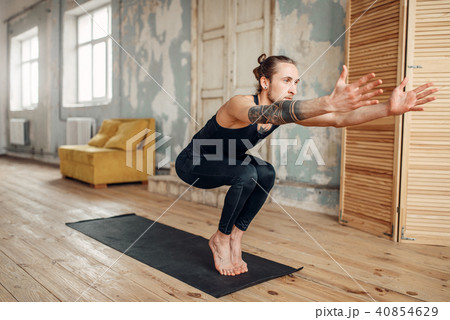 Male yoga doing balance exercise on mat in gym 40854629