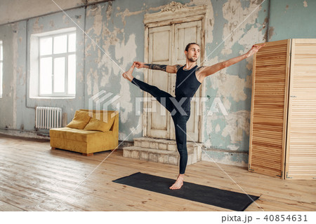 Male yoga doing balance exercise on mat in gym 40854631