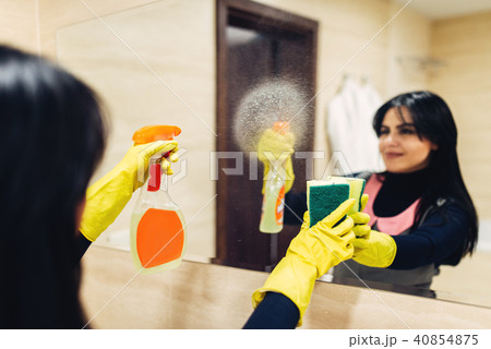 Housemaid cleans the mirror with a cleaning spray 40854875