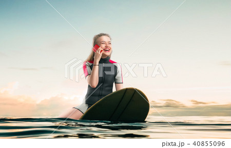 Windsurfer sitting on board and talks by phone Windsurfer sitting on board and talks by phone 40855096
