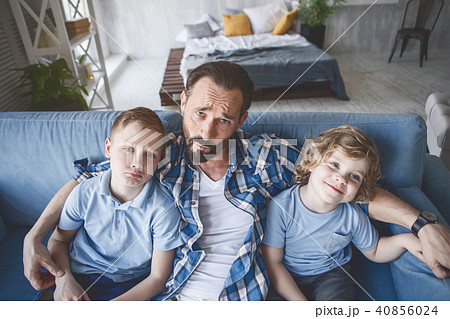 Wailful dad hugging kids on couch 40856024
