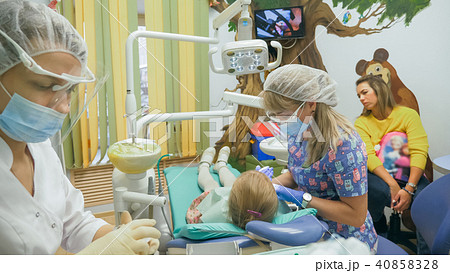 Child with a mother at a dentist's reception. The girl lies in the chair, behind her mother. The Child with a mother at a dentist's reception. The girl lies in the chair, behind her mother. The 40858328