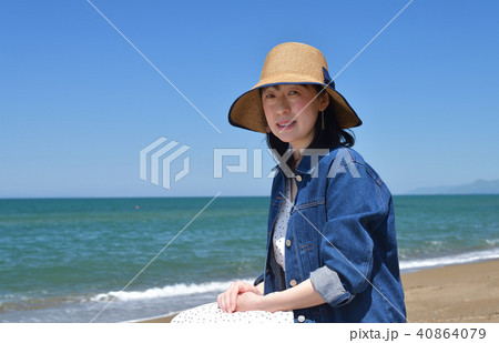 砂浜の海岸で快晴の青空をバックにジージャンにストローハットの女性のポートレートを撮影 40864079