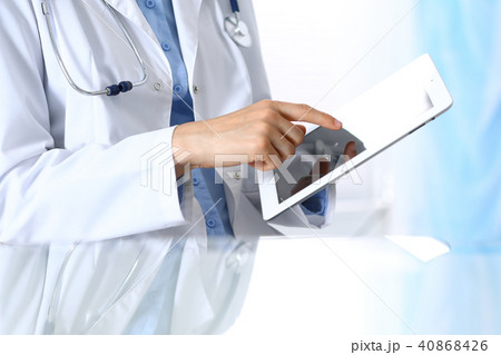 Woman doctor using tablet computer while sitting. Reflecting glass table is a working place of Woman doctor using tablet computer while sitting. Reflecting glass table is a working place of 40868426