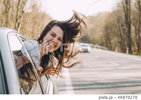 young pretty woman stick out of car window. wind blowing woman hair 40870270