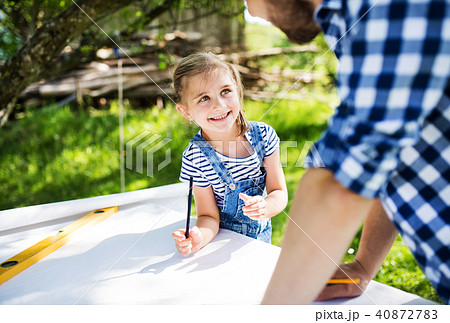Father with a small daughter outside, planning wooden birdhouse. 40872783