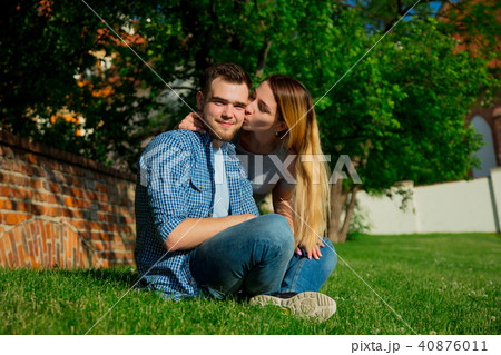 Young couple sitting on a green grass Young couple sitting on a green grass 40876011