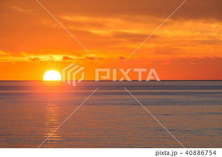 穏やかな海に沈む夕日の写真素材