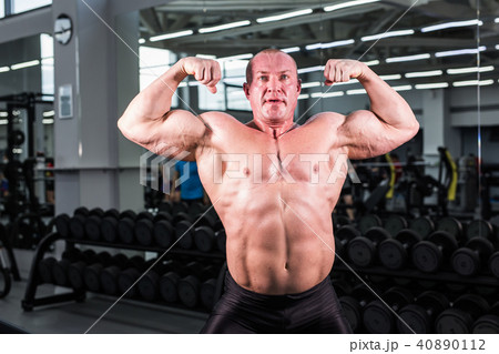 Bodybuilder man with perfect biceps, triceps and chest in the gym Bodybuilder man with perfect biceps, triceps and chest in the gym 40890112