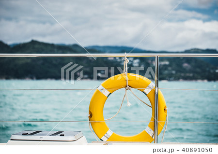 Close-up Yellow life ring hanging on boat with ocean background. 40891050