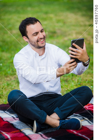 Modern young hispanic man taking a selfie at the park, with his tablet. Modern young hispanic man taking a selfie at the park, with his tablet. 40897760