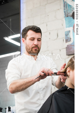 Male hairdresser making haircut for a client in professional hairdressing salon 40898499