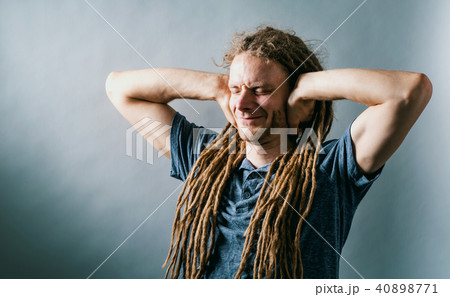Young man blocking his ears on a solid background 40898771