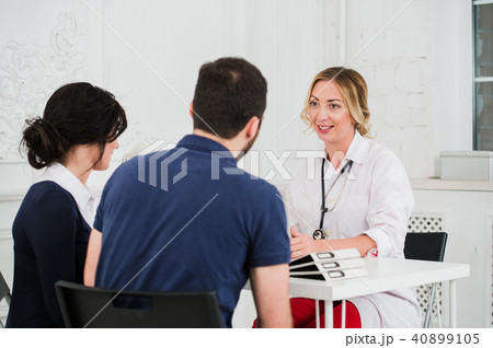 Two pretty young women nurses or doctors talking with female client in their office Two pretty young women nurses or doctors talking with female client in their office 40899105