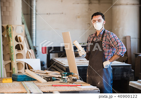 Horizontal view of professionally dressed carpenter varnishing a board Horizontal view of professionally dressed carpenter varnishing a board 40900122